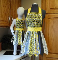 two mannequins wearing aprons on top of a kitchen counter next to each other