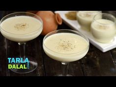 two glasses filled with white liquid sitting on top of a table next to an egg