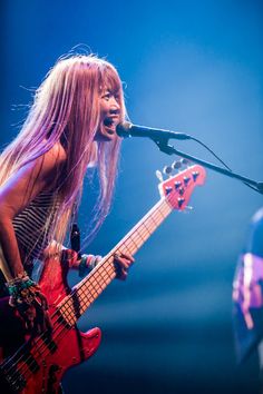 a woman singing into a microphone while holding a guitar