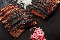 the steak is sliced and ready to be served on the grill with onion wedges next to it