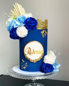 a blue and gold cake with flowers on top