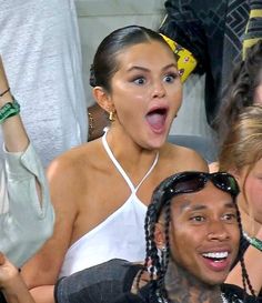 a woman with her tongue out in front of two other people at a sporting event