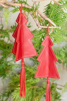 two red leather christmas trees hanging from a tree branch