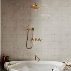 a white bath tub sitting under a faucet next to a wall mounted shower head