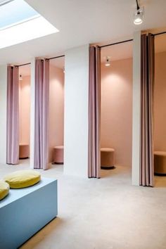 an empty room with pink curtains and yellow pillows on the floor in front of it