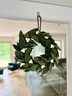 a wreath with white flowers hanging from the side of a door in front of a living room