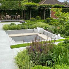 an outdoor seating area surrounded by greenery and flowers in the middle of a garden