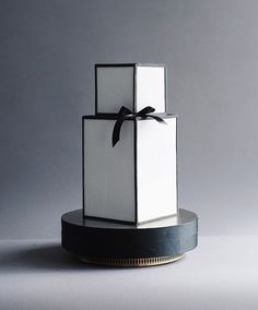 a white box with a black bow on it sitting on top of a round base