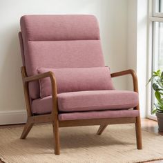 a pink chair sitting on top of a rug next to a potted green plant