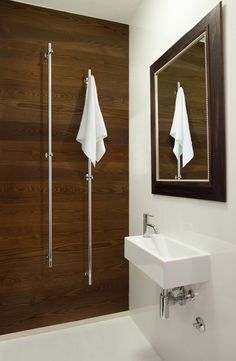 a white sink sitting under a bathroom mirror next to a wooden wall with two towels hanging on it