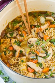 a pot filled with chicken noodle soup and chopsticks sticking out of it