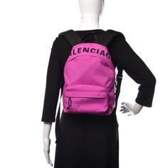 Balenciaga Nylon Wheel Logo Backpack Fuchsia. This stylish backpack is crafted of nylon in fuchsia. The bag features an embroidered black Balenciaga logo across the top, a front zipper pocket, a black canvas top handle, and adjustable padded black shoulder straps. The wrap-around silver zippers open the bag to a black nylon interior with zipper and patch pockets. This lovely backpack is spacious enough for all of your necessities, with the fashion forward appeal of Balenciaga!    Model: 565798 Designer Nylon School Bags, Designer Nylon School Backpack, Nylon Bag With Embroidered Logo For Everyday Use, Everyday Nylon Bags With Embroidered Logo, School Nylon Bag With Logo, School Nylon Bags With Logo, Nylon Logo Backpack, Designer Pink Backpack, Logo Nylon Backpack