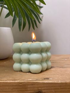 a small candle that is sitting on a table next to a potted palm tree