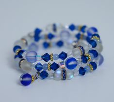 "Rhapsody In Blue"- This work of art evokes the same originality as it's symphonic namesake.  The wearer is the kind of person who adds their own fresh perspective to the traditional, while challenging the world with their own uniqueness. A beautiful memory wire bracelet with blue Preciosa crystals. Our bracelets are creative, one of a kind pieces, each with their own unique names. No two bracelets are the same. This bracelet comes in an adorable cat shaped cotton crocheted pouch for safe keeping. The perfect gift or fashion accessory! Wire Wrapped Blue Beaded Bracelets For Gift, Wire Wrapped Blue Beaded Bracelets As Gift, Blue Wire Wrapped Beaded Bracelets As Gift, Blue Wire Wrapped Beaded Bracelet For Gift, Wire Wrapped Blue Beaded Bracelet As Gift, Blue Hand Wrapped Crystal Bracelet As Gift, Blue Spiritual Wrap Bracelet As Gift, Blue Spiritual Style Wrap Bracelet As Gift, Hand Wrapped Blue Crystal Bracelet For Healing