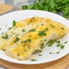 a white plate topped with an omelet covered in cheese and green garnish