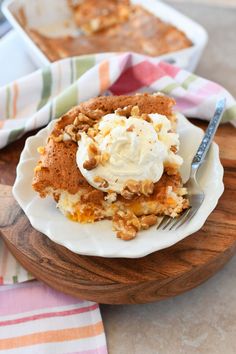 a piece of cake on a plate with whipped cream and walnuts next to it