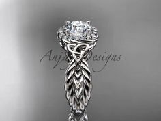 an intricately designed engagement ring with a center stone and leaves on the band, set in