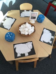 a wooden table topped with cards and dices next to a bowl of marshmallows