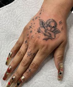 a woman's hand with an angel tattoo on it and stars around her fingers