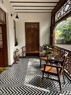 an empty porch with chairs and potted plants