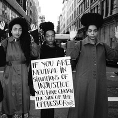 black and white photograph of three women holding protest signs in the middle of an urban street