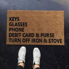 someone standing in front of a door mat that says keys glasses phone debt card and purse turn off iron & stove