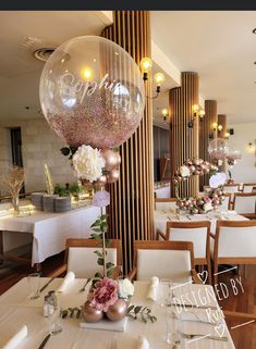 a dining room filled with lots of tables covered in white tablecloths and balloons