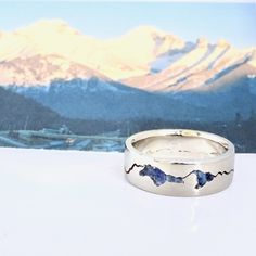 two wedding rings with mountains in the background