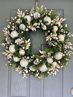 a wreath with white balls and greenery is hanging on the front door to welcome guests