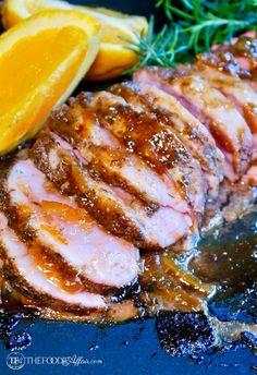 sliced pork with oranges and rosemary on the side