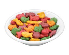 a white bowl filled with lots of different colored dog treats