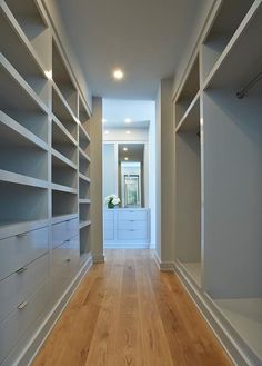 an empty walk - in closet with white shelving and wood flooring is shown