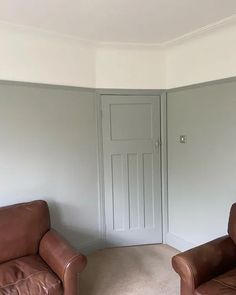 two brown leather chairs sitting in front of a white wall with a door on the other side