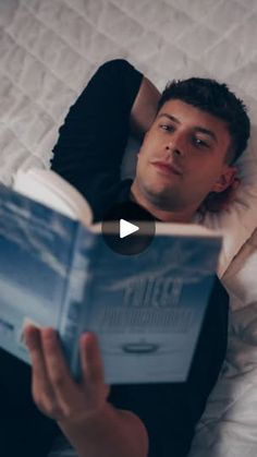 a man laying in bed reading a book