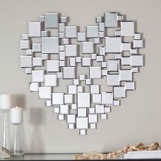 a heart shaped mirror hanging on the wall next to a candle and vase with flowers