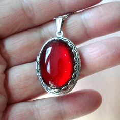 This beautiful locket is adored with a large 18x25 Ruby Red Green glass gem stone. Size: 24x30mm Chain Length: Per Option Qty: 1pc Gift Cabochon Metal Necklace, Handmade Red Oval Necklace, Vintage Red Resin Jewelry, Oval Amber Necklace For Gift, Amber Locket Jewelry As A Gift, Amber Locket Jewelry For Gift, Nickel-free Red Jewelry For Gifts, Nickel Free Red Jewelry As Gift, Nickel-free Red Jewelry Gift