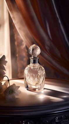 a glass perfume bottle sitting on top of a table next to a white and pink flower