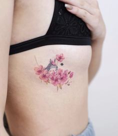 a woman's stomach with pink flowers and a bird tattoo on the side of her belly