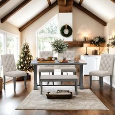 a dining room table with chairs and a christmas tree in the corner on the far wall