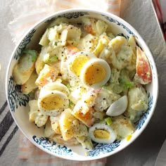 a bowl filled with pasta and eggs on top of a tablecloth next to utensils