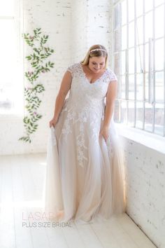 a woman in a wedding dress leaning against a wall with her hands on her hips