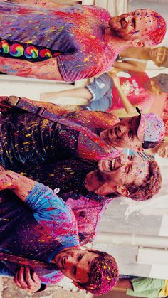 two men covered in colored paint standing next to each other and looking at the camera