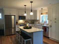 a kitchen with white cabinets and an island in front of the stove, refrigerator and sink