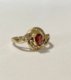 Stunning and classic vintage 14k yellow gold garnet and diamond bypass ring. The mid-century ring features a beautiful pear shaped garnet and ten Baguette cut diamonds with six brilliant cut diamonds accenting the shoulders. ERA - Circa 1970, Mid-Century METAL / MATERIAL - 14k yellow gold, one pear shaped garnet ( approx, .39 ct) ten Baguette diamonds (approx. .25 ct), six brilliant cut diamonds (.25 ct) MARKINGS / HISTORY - 14k CONDITION - Good vintage condition. Garnet & Diamonds are secur Vintage Garnet Rings, Star Garnet, Pear Shaped Ring, Garnet Gem, Bypass Ring, Eyes Open, Baguette Diamonds, January Birthstone, Garnet Ring