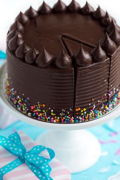 a chocolate cake with sprinkles on a plate next to a blue ribbon