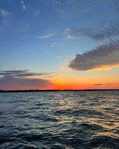 the sun is setting over the water with clouds in the sky