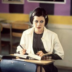 a woman sitting at a desk with a book and pen in her hand