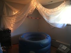 an inflatable pool with lights hanging from the ceiling and curtains on the wall