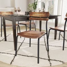 a dining room table with chairs and a rug on the floor