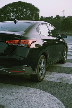 the back end of a black car parked in a parking lot